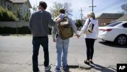 Sepasang suami istri AS mengantar anak mereka, Ben, didiagnosa menderita autis sejak umur 2,5 tahun, menyeberang jalan di New Orleans, Louisiana (foto: ilustrasi). 