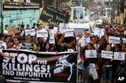 FILE - Protesters and supporters carry banners and placards as they march with the hearse of slain Kian Loyd delos Santos, a 17-year-old student, during his funeral, Aug. 26, 2017, in suburban Caloocan city north of Manila, Philippines.