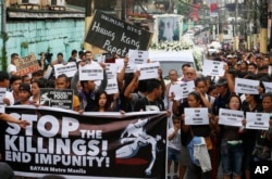 FILE - Protesters and supporters carry banners and placards as they march with the hearse of slain Kian Loyd delos Santos, a 17-year-old student, during his funeral, Aug. 26, 2017, in suburban Caloocan city north of Manila, Philippines.