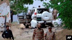 Los funcionarios de seguridad paquistaníes están de guardia en el sitio de un atentado suicida que mató a docenas de personas y dejó a muchos heridos en el distrito de Mastung cerca de Quetta, Pakistán, el viernes 12 de mayo de 2017.