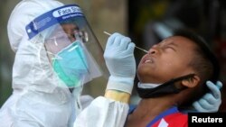 A medical worker performs a nose swab on a migrant boy at a seafood market, amid the coronavirus disease (COVID-19) outbreak, in Samut Sakhon province, in Thailand, December 19, 2020. REUTERS/Panumas Sa