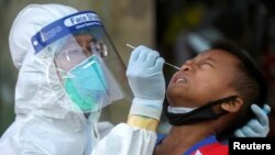 A medical worker performs a nose swab on a migrant boy at a seafood market, amid the coronavirus disease (COVID-19) outbreak, in Samut Sakhon province, in Thailand, December 19, 2020. REUTERS/Panumas Sa