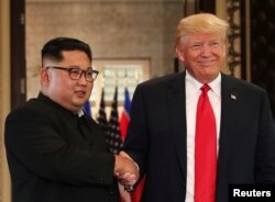 U.S. President Donald Trump and North Korea's leader Kim Jong Un shake hands after signing documents during a summit at the Capella Hotel on the resort island of Sentosa, Singapore, June 12, 2018.