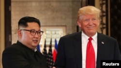 Presiden AS Donald Trump dan pemimpin Korea Utara Kim Jong Un berjabat tangan setelah menandatangani dokumen dalam pertemuan puncak di Hotel Capella, Pulau Sentosa, Singapura, 12 Juni 2018.