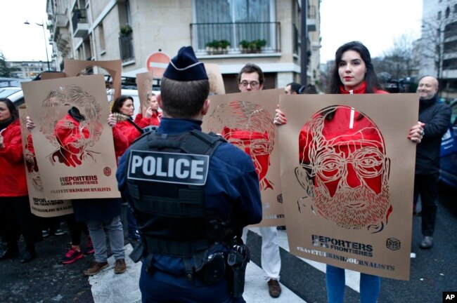 Anggota Wartawan Tanpa Tapal Batas memegang stensil yang mewakili potret para wartawan Turki yang ditahan, dalam sebuah pawai di depan Kedutaan Besar Turki di Paris, 5 Januari 2018.