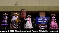 FILE - Members of the Latino community hold signs as former vice president and then-Democratic presidential candidate Joe Biden meets with Latino leaders at East Las Vegas Community Center, in Las Vegas, Nevada, Oct. 9, 2020.