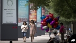 2013年6月26日，一位攤販坐在北京街頭人行道上販賣氣球。