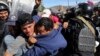 Para migran Amerika Tengah bentrok dengan polisi Meksiko setelah berusaha menerobos pagar perbatasan AS di kota Tijuana, Meksiko, Minggu (25/11). 