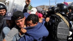 Migrantes centroamericanos chocan con la policía mexicana en la forntera entre México y EE. UU., en el cruce de Chaparral en Tijuana, México, el domingo 25 de noviembre de 2018.