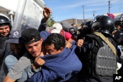 Migrants clash with Mexican police at the Mexico-U.S. border after getting past another line of Mexican police at the Chaparral crossing in Tijuana, Mexico, Sunday, Nov. 25, 2018