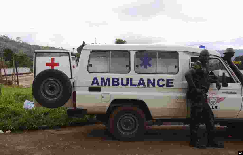 Un soldat Cameroun, à droite, se tient à côté d'une ambulance utilisée pour transporter les victimes du déraillement d'un train vendredi à Eseka, Cameroun, 22 octobre 2016.