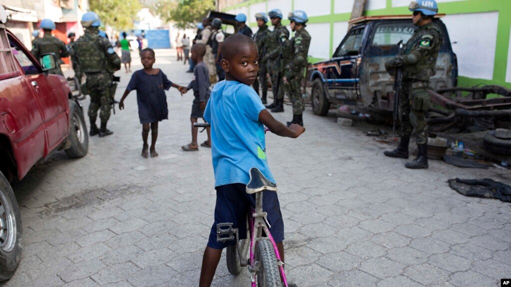 FILE - Children play in the street while United Nations peacekeepers from Brazil patrol in the Cite Soleil slum, in Port-au-Prince, Haiti, Feb. 22, 2017. 