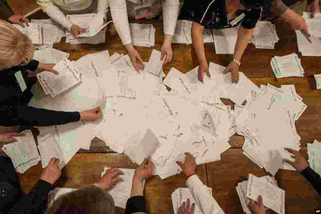Para anggota komite pemilihan umum menghitung suara setelah pemungutan suara ditutup di sebuah TPS di Donetsk, Ukraina (11/5). (AP/Evgeniy Maloletka)