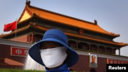 Женщина в маске на площади Тяньаньмэнь в центре Пекина, Китай
