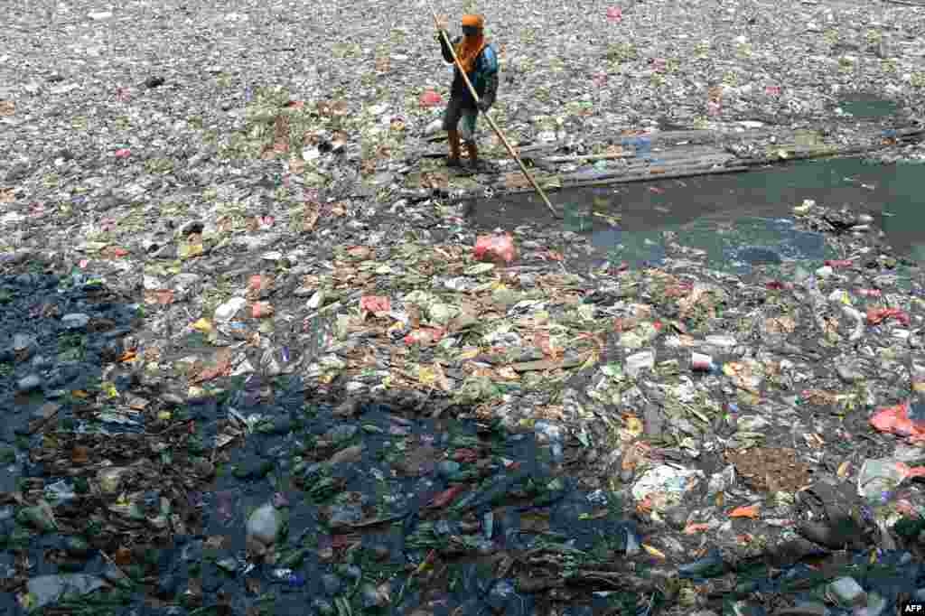 Seorang pekerja Indonesia membersihkan sungai di Jakarta. Menurut laporan kantor Lingkungan Hidup Juni 2013, sekitar 82 persen dari 52 sungai yang disurvei tercemar oleh limbah rumah tangga dan limbah industri.
