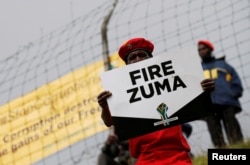 FILE - Supporters of various opposition parties hold placards calling for the removal of President Jacob Zuma outside the Constitutional Court in Johannesburg, South Africa, May 15, 2017.