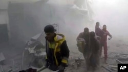 This frame grab from video released Feb 24, 2018, by the Syrian civil defense group known as the White Helmets shows members of the group helping residents during airstrikes and shelling by Syrian government forces, in Ghouta, a suburb of Damascus, Syria.