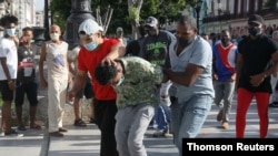 Policías vestidos de civil detienen a una persona durante protestas en contra y en apoyo al gobierno, en La Habana, el domingo 11 de julio de 2021.