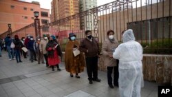 A health worker speaks with people in line for shots of the Sinopharm COVID-19 vaccine inside Universidad Mayor de San Andres public university during vaccinations for people over age 50 in La Paz, Bolivia, May 17, 2021. 