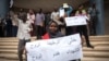 Susana Abdalla Hassan, an employee of Bank of Khartoum, holds a sign supporting the revolution while striking outside Al-Waha mall, in Khartoum, Sudan, May 28, 2019.