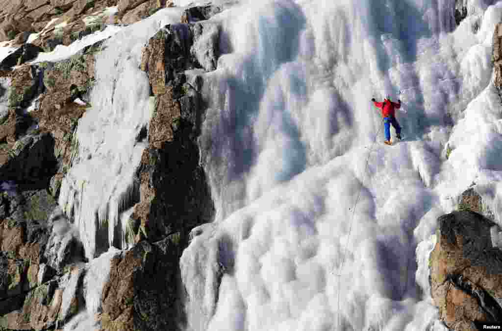 Seorang pria berusaha memanjat gunung karang yang diselimuti es (salju) di sebuah glacier di Presena, Italia utara.