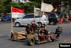 FILE - Extreme Vespa enthusiasts drive near the site of a weekend scooter festival in Kediri, East Java, Indonesia, Aug. 5, 2018.