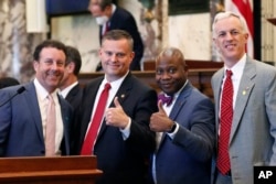 Sens. David Parker, R-Olive Branch, left, Chad McMahan, R-Guntown, Derrick Simmons, D-Greenville, second from right, and David Blount, D-Jackson, right, strike a congratulatory pose after the Senate voted to change the Mississippi state flag.