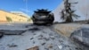 Mobil yang hangus dans selongsong peluru tampak di jalanan Tripoli, pasca bentrokan antar milisi hari Minggu (28/8). 