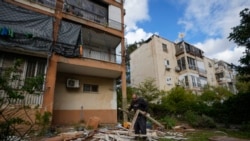 Seorang pria sedang bekerja di dekat sebuah gedung yang rusak terkena serangan rudal yang diluncurkan dari Yaman dan mendarat di distrik Jaffa, Tel Aviv, Israel, Selasa, 31 Desember 2024. (Foto: Mathias Delacroix/AP Photo)