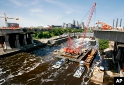 FILE - A section of the new I-35 bridge is raised from a barge in the Mississippi River at Minneapolis, Minnesota, June 24, 2008. The I-35W bridge was rebuilt in less than 14 months.