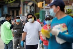 People wearing protective face masks wait in line at a food bank at St. Bartholomew Church, during the outbreak of the coronavirus disease, in the Elmhurst section of Queens, New York City, May 15, 2020.