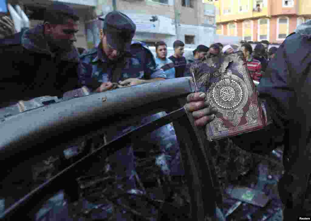 A man holds a copy of the Koran after an Israeli air strike on a car of Hamas military chief Ahmed al-Jaabari in Gaza City, November 14, 2012.