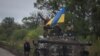 在刚从俄军手中收复的乌克兰东北部哈尔科夫州伊久姆镇，乌克兰军人站在竖着乌克兰国旗的BMP-1步兵战车上。（2022年9月14日）