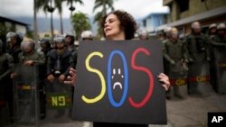 Una manifestante sostiene un cartel durante protestas frente a la fuertemente custodiada embajada cubana en Caracas.