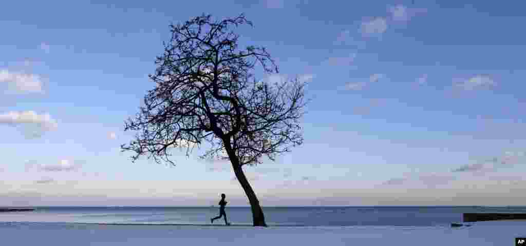 A lone runner traverses the bike and running path along Lake Michigan at the North Avenue beach as temperatures hover around freezing in Chicago, Dec. 17, 2013. 