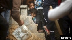 Boys watch the burial of Yassin Abu Khoussa, a 10-year-old Palestinian killed in an Israeli airstrike in the northern Gaza Strip, March 12, 2016. The boy's sister, 6-year-old Israa, later died.