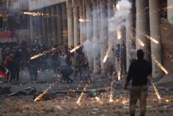 FILE - Iraqi demonstrators throw fireworks toward Iraqi security forces during the ongoing anti-government protests in Baghdad, Iraq, Nov. 23, 2019.
