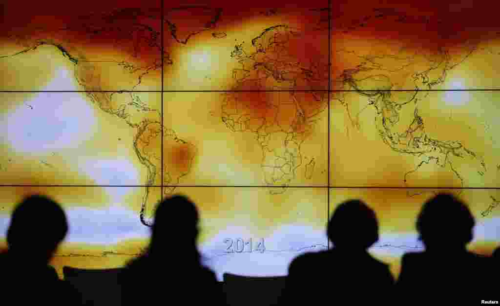 Participants are seen in silhouette as they look at a screen showing a world map with climate anomalies during the World Climate Change Conference 2015 (COP21) at Le Bourget, near Paris, France.