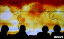 Participants are seen in silhouette as they look at a screen showing a world map with climate anomalies during the World Climate Change Conference 2015 (COP21) at Le Bourget, near Paris, France, December 8, 2015.
