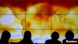 Participants are seen in silhouette as they look at a screen showing a world map with climate anomalies during the World Climate Change Conference 2015 (COP21) at Le Bourget, near Paris, France, December 8, 2015. 
