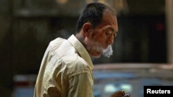 A taxi driver takes a cigarette break in central Beijing, China, May 28, 2012.