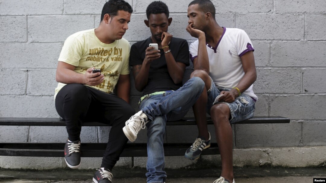 Jóvenes usan el internet por medio de servicio wifi gratis cerca de un estudio de arte en La Habana.