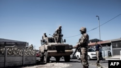 South African National Defense Force (SANDF) soldiers stand next to an Armored Personnel Carrier in the Cape Flats area of Cape Town, on March 30, 2020, during a patrol to enforce a nationwide lockdown. 