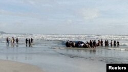 Orang-orang melakukan pencarian korban di pantai Tanjung Balau setelah sebuah kapal yang membawa para migran terbalik, di Kota Tinggi, Johor, Malaysia, 15 Desember 2021. (Royal Malaysian Army/Handout via REUTERS)