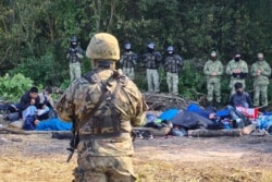 Armed Polish soldiers and Afghan refugees who have fled the Taliban are seen in eastern Poland on the border to Belarus, August 20, 2021.