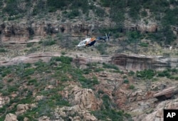 FILE - A helicopter flies above the rugged terrain along the banks of the East Verde River during a search and rescue operation for victims of a flash flood in Payson, Arizona, July 16, 2017.