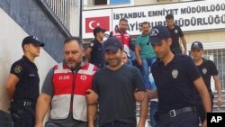 FILE - Turkish police officers escort Turkish pop singer Atilla Tas, center, to police headquarters following his arrest, in Istanbul, Turkey, Sept. 3, 2016.