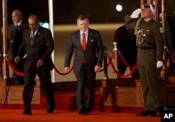 Jordan's King Abdullah II, center, greets Sudan's President Omar al-Bashir, left, upon his arrival at Queen Alia International Airport in Amman, Jordan, March 28, 2017. Bashir is among 21 Arab leaders gathering for a summit.