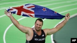 Atlet Selandia Baru Tomas Walsh merayakan kemenangannya dalam Pertandingan Atletik Dunia di Portland, Oregon, dengan membawa benderanya berlari keliling lapangan, 18 Maret 2016 (Foto: dok). 