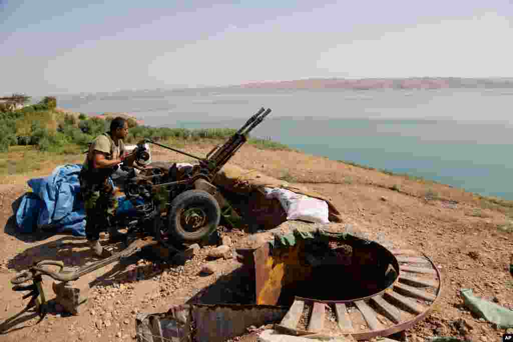 A Kurdish peshmerga fighter prepares his weapon at his combat position at the Mosul Dam, outside Mosul, Iraq, Aug. 17, 2014.